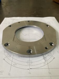 Componente Meccanico, ovvero una Flangia, poggiata su un disegno tecnico